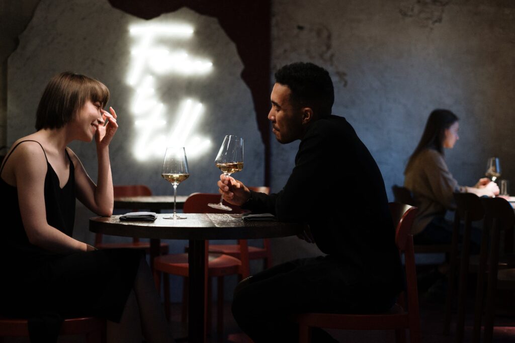 libra man in black long sleeve shirt sitting on chair across from libra woman on a date